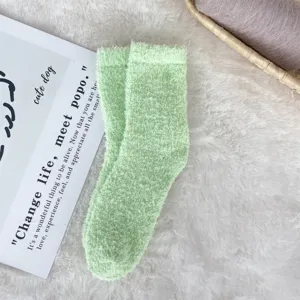 Detailed view of soft mint green coral fleece fuzzy socks on a plush white background
