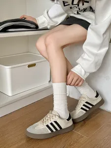 Ribbed white mid-calf slouch socks styled with classic retro leather sneakers on wooden floor