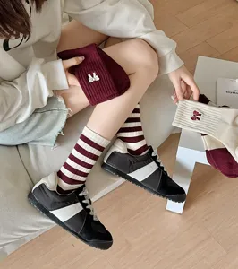 Close-up van bordeauxrode gestreepte sokken met strikborduursel en casual sportieve schoenen