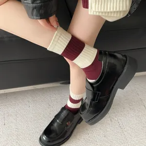 Detail van bordeauxrode en crèmekleurige gestreepte halfhoge sokken met loafers