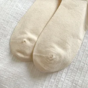 Detailopname van crèmekleurige gebreide sokken met zachte textuur en teennaad