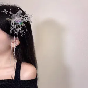 Détail d'une pince à cheveux papillon en cristal avec des perles irisées et pompons