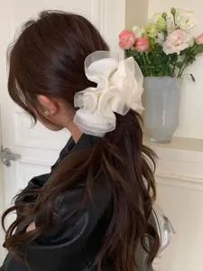 Elegantes Detail eines großen, plissierten, cremefarbenen Organza-Haargummis am Zopf.