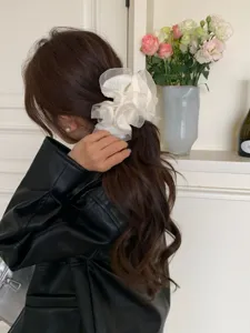 Eleganter übergroßer weißer Organza-Haargummi mit Rüschenfalten auf gewelltem Haar