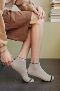 Close-up of men's beige low-cut boat socks worn by a model in a lifestyle setting