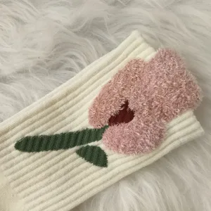 Close-up detail of pink fuzzy tulip embroidery on cream ribbed autumn winter socks