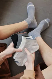 Close-up detail of men's ribbed low-cut cotton boat socks in various neutral colors