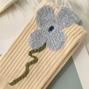 Close-up showing the plush grey flower detail on a cozy beige ribbed winter sock
