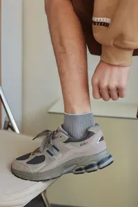 Close-up of grey ribbed men's socks worn with lifestyle sneakers.