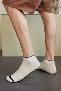 Detailed side view of premium low-cut men's beige cotton boat socks on a model