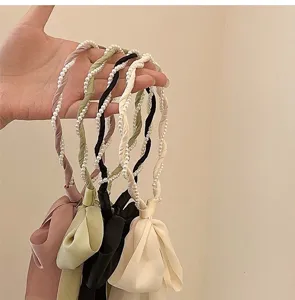 Detalle de diademas trenzadas de perlas y satén con elegantes lazos de cinta largos.