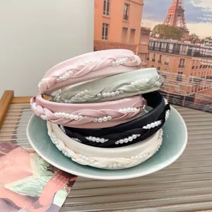 Elegante gevlochten parel haarbanden in diverse pastelkleuren op een mooi keramisch bord.
