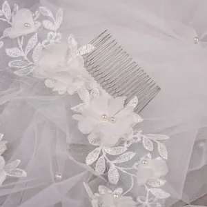 Close-up of elegant bridal hair comb with lace flowers and pearls on a white veil