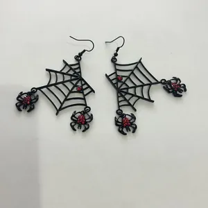 Détail des boucles d'oreilles toile d'araignée noires d'Halloween avec strass rouges étincelants.