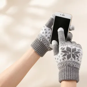 Detail of gray snowflake knitted gloves with touchscreen fingertips holding a white smartphone