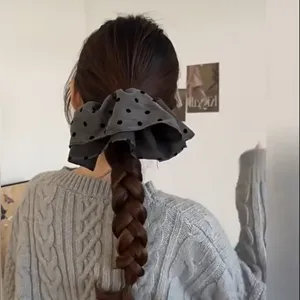 Λεπτομερής προβολή μεγάλου γκρι scrunchie με πουά σε ένα χτένισμα με πλεξούδα