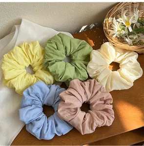Close-up view of five pastel solid color oversized scrunchies with soft matte fabric texture