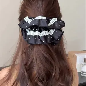 Detailed view of large black polka dot scrunchie with white lace trim on hair