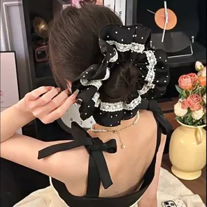 Close-up of a large black polka dot hair scrunchie with lace trim shown on a hair bun