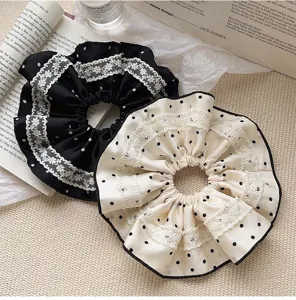 Macro detail of lace and polka dot patterns on oversized fabric hair scrunchies.