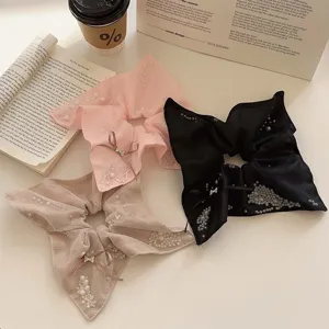 Elegant pearl scrunchies with bow details in pink, beige, and black mesh fabric.