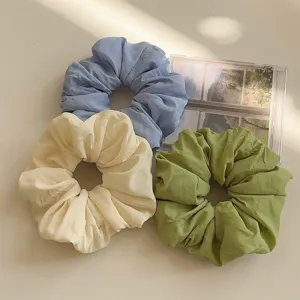 Elegant oversized fabric hair scrunchies set in pastel blue, cream, and muted green tones.