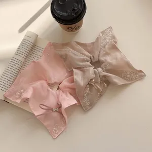 Elegant pearl bow hair scrunchies in pink and beige shown on an aesthetic background