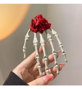 Detailansicht einer gotischen Skeletthand-Haarspange mit roten Stoffrosen-Akzenten.
