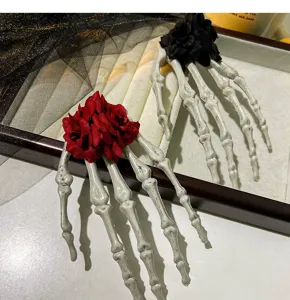 Detailaufnahme einer gotischen Skeletthand-Haarklammer mit realistischen roten Rosen