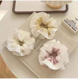 Détail d'élastiques à cheveux à double couche avec dentelle plissée aux tons crème.
