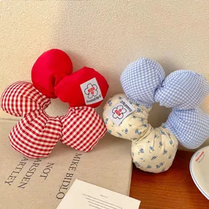 Detailansicht großer Plüsch-Haargummis mit rotem Gingham- und blauem Blumenmuster