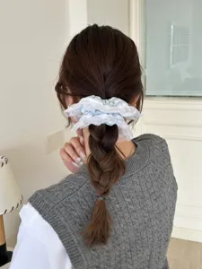 Blau gestreifter Spitzen-Scrunchie an einem geflochtenen Pferdeschwanz