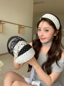 Vue détaillée de bandeaux larges à pois et fleurs élégants tenus par un mannequin.