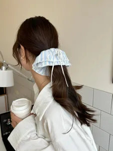 Blau gestreiftes Spitzen-Scrunchie mit weißer Schleife, von einem Model getragen.