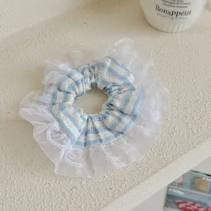 Detailaufnahme eines blau-weiß gestreiften Haargummis mit feiner weißer Spitze.