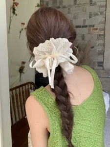 Detail of white lace scrunchie with adjustable ribbon bow on braided hair.