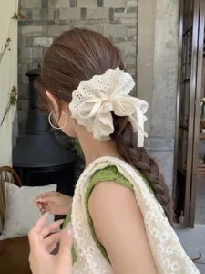 Back view of a large cream lace scrunchie with a ribbon bow on braided hair.