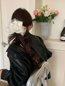 Detailaufnahme eines weißen Organza-Haargummis mit Rüschen am Pferdeschwanz eines Models