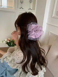 Detailansicht eines großen lila gerafften Haargummis aus Organza in langem Haar.