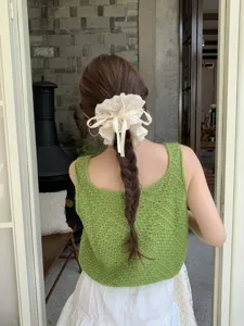 Detail of a large white lace scrunchie with adjustable ribbon on a braided hairstyle.