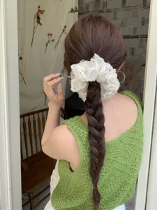 Close-up detail of a romantic white lace embroidered scrunchie styled on a braided ponytail.