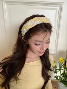 Close-up of a model wearing a stylish yellow and white lace braided headband accessory