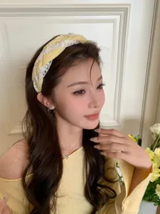 Detailed view of an elegant yellow lace headband worn by a model in a soft setting