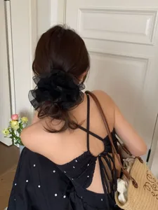 Detailansicht eines großen schwarzen Organza-Haargummis, das in einem Dutt sitzt.
