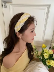Close-up of elegant yellow and white lace braided wide headband on model