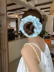 Macro detail showing a four-layer light blue lace drawstring scrunchie on a hair bun