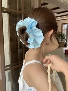 Detailed view of light blue lace scrunchie with ribbon on elegant female bun hairstyle