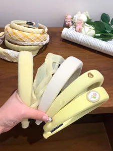 Detail view of collection featuring various yellow and cream padded headbands held by hand