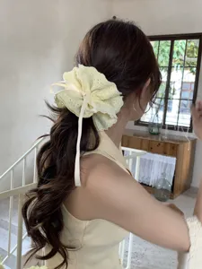 Close-up detail of a cream floral lace drawstring scrunchie worn on a stylish low ponytail