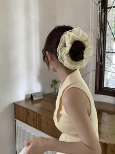 Detail view showing a yellow romantic lace embroidered scrunchie on a bun hairstyle